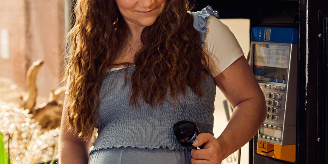 Pregnant woman holding a public phone receiver
